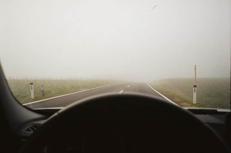 Driving through dense fog on a country road, limited visibility ahead.
