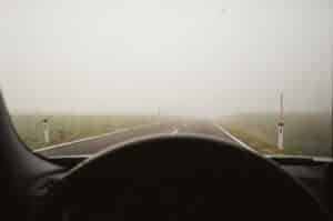 Driving through dense fog on a country road, limited visibility ahead.